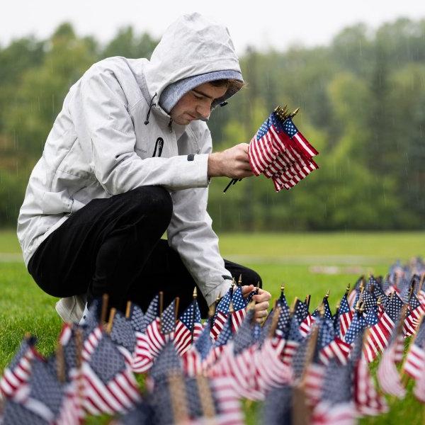 一个人跪在地上，把小美国国旗插在地上.